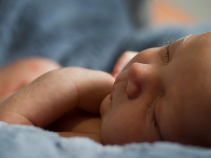 Baby sleeping peacefully with their parent watching over them in the background
