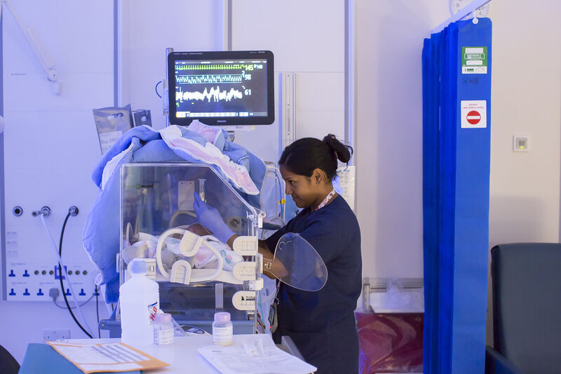 Hospital nurse caring for baby in incubator