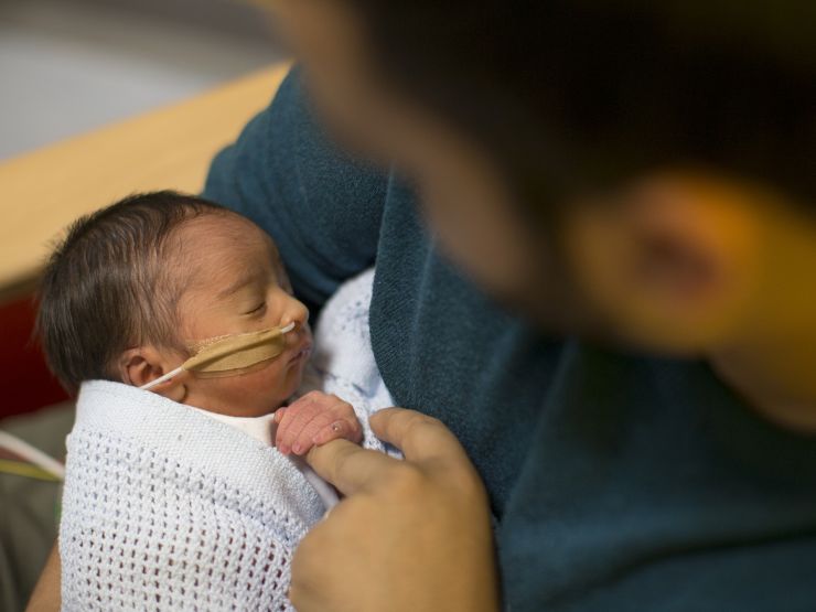 Looking down on dad holding baby with baby holding dad's finger