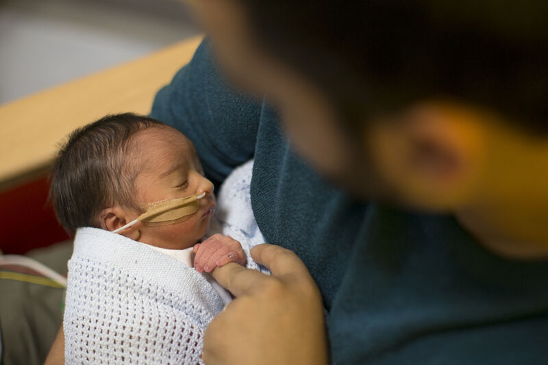 Looking down on dad holding baby with baby holding dad's finger