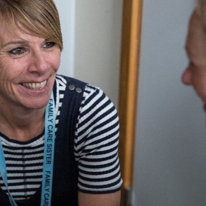Two professionals sitting down and talking together smiling at each other
