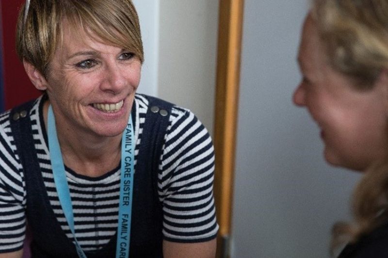 Two professionals sitting down and talking together smiling at each other