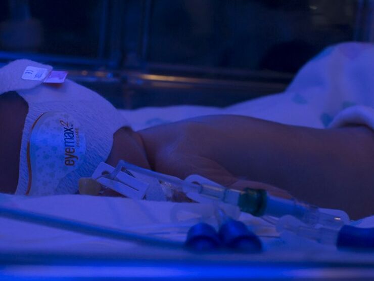 Baby lying in cot with mask on