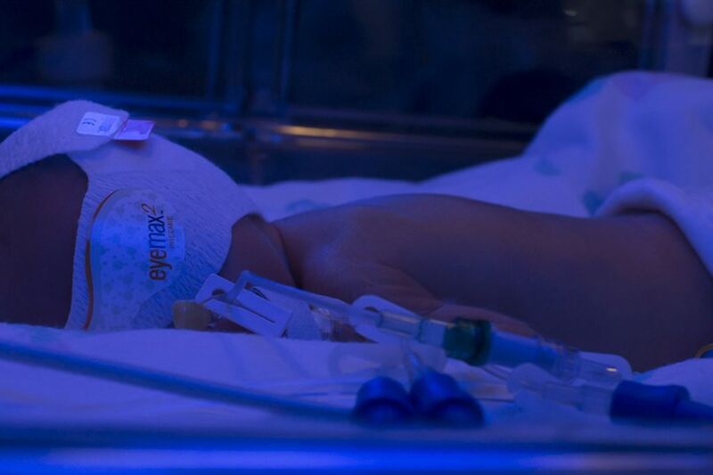 Baby lying in cot with mask on