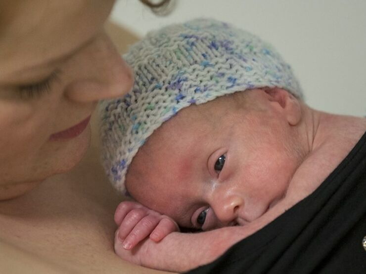 Mum cuddling baby into her skin to skin