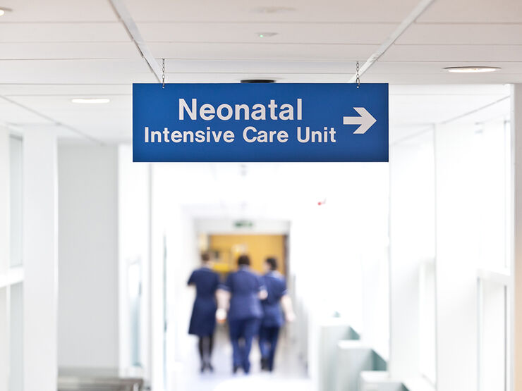 Hospital sign for neonatal intensive care unit with nurses blurred in background