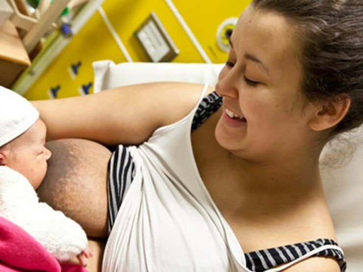 Baby breastfeeding with mum smiling down at baby