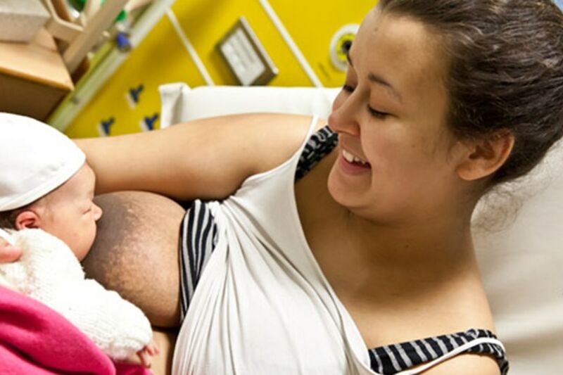 Baby breastfeeding with mum smiling down at baby