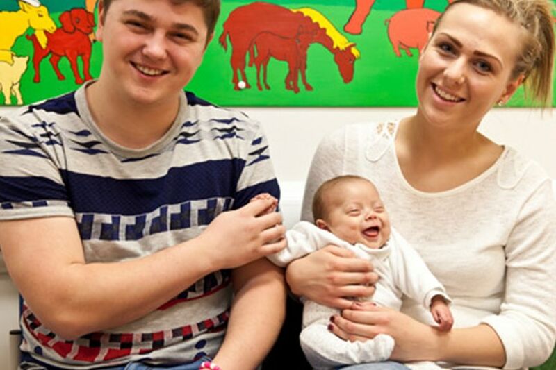 A couple with their baby smiling at camera about to go home