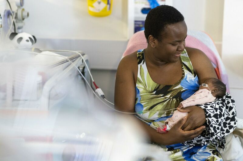 A mum holding her baby while the baby is attached to some wires