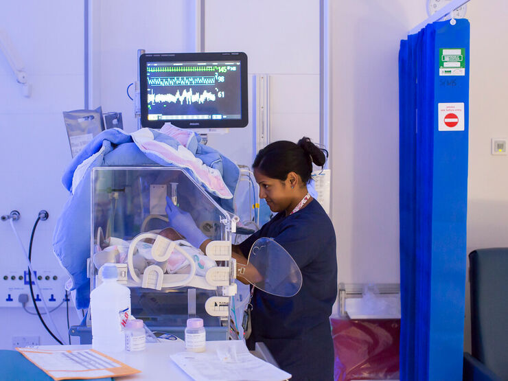 Nurse caring for baby in incubator