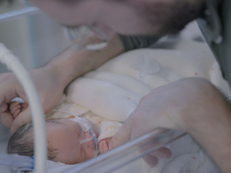 Father looking down and caressing his sleeping baby.