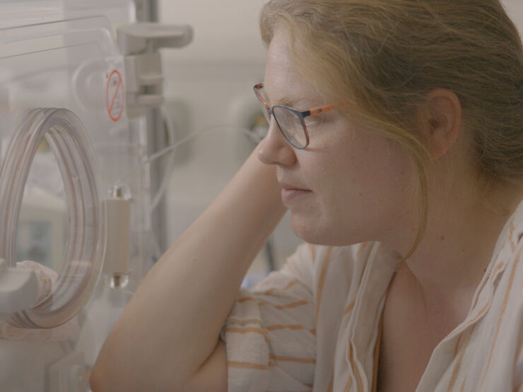 Mother gazing intently at her child in an incubator
