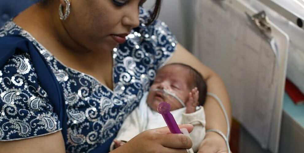 Mum holding baby in her arms while tube feeding her