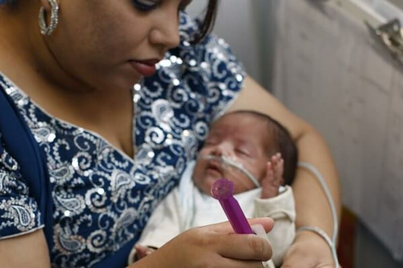 Mum holding baby in her arms while tube feeding her