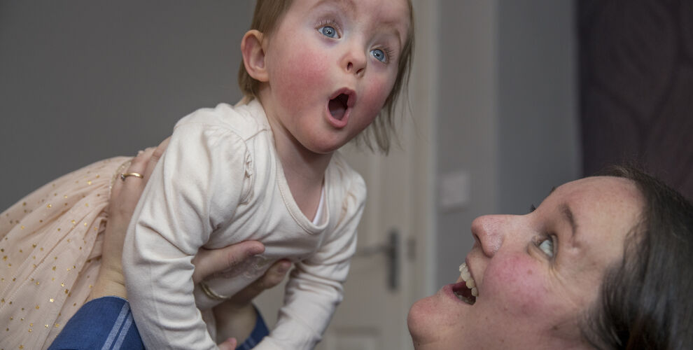 Mother lifting up her baby daughter playfully