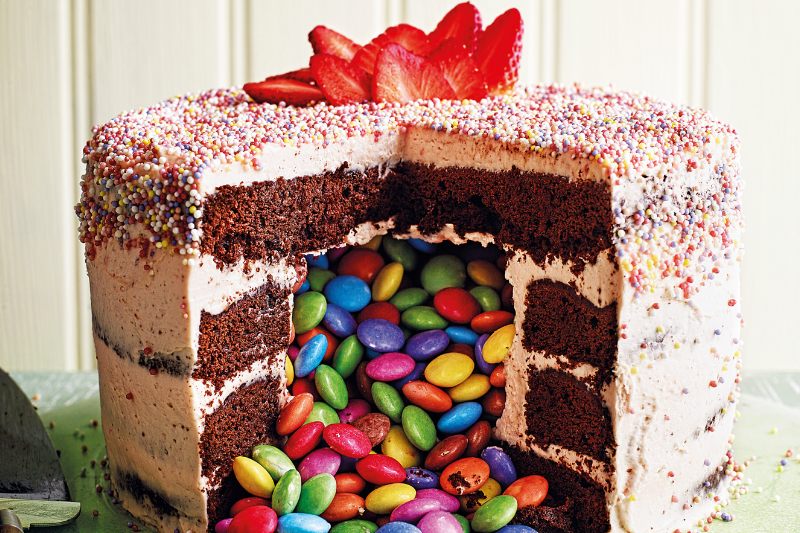 Cake with slice taken out and smarties tumbling out from the middle