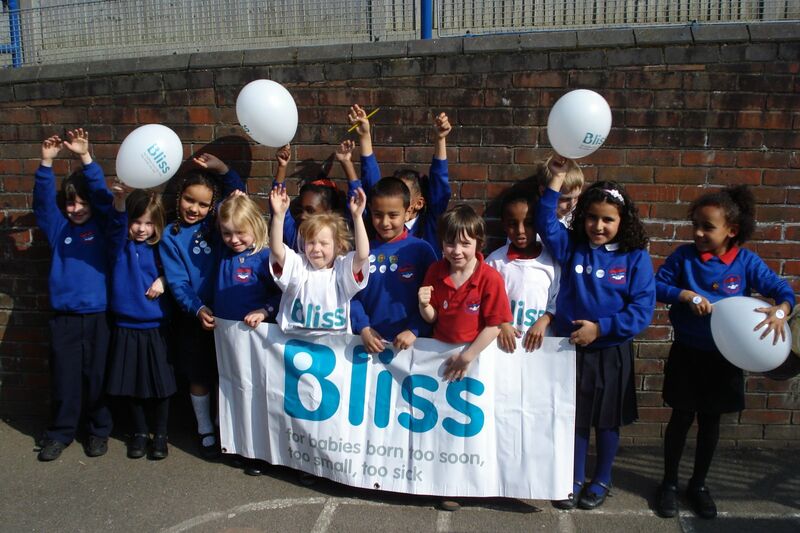 group of school children with Bliss banner and balloons