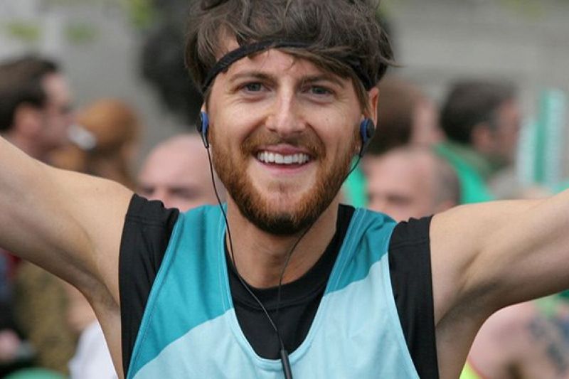 Head shot of man running celebrating with arms in the air at an event wearing a Bliss running vest