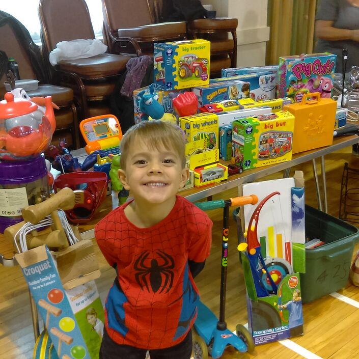 Young boy in spider man costume in front of his toys