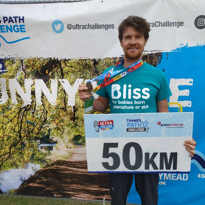 Man in bliss t-shirt with medal having finished 50km challenge