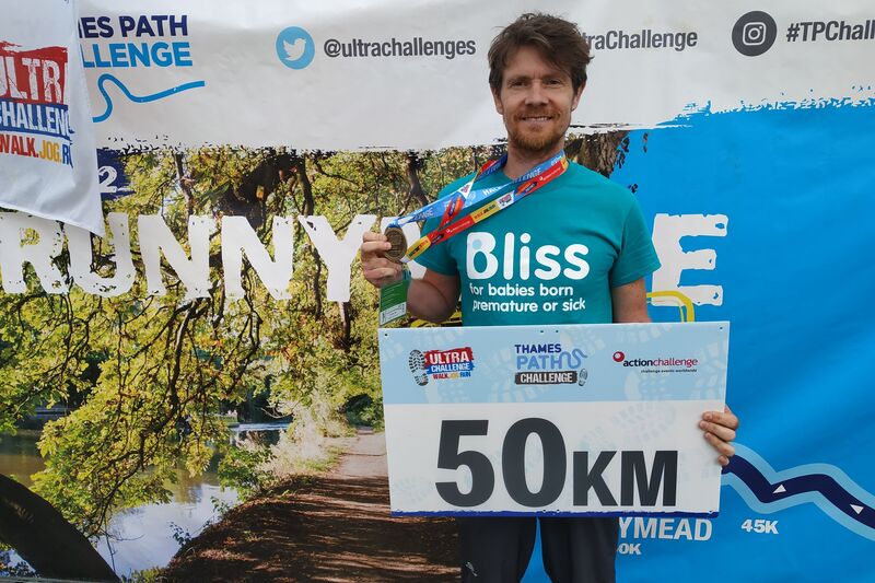 Man in bliss t-shirt with medal having finished 50km challenge