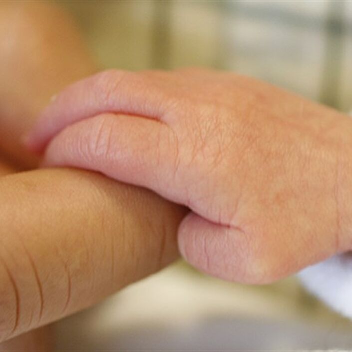 Baby hand holding a finger of an adult