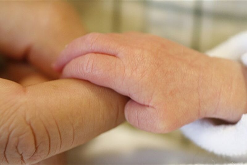 Baby hand holding a finger of an adult