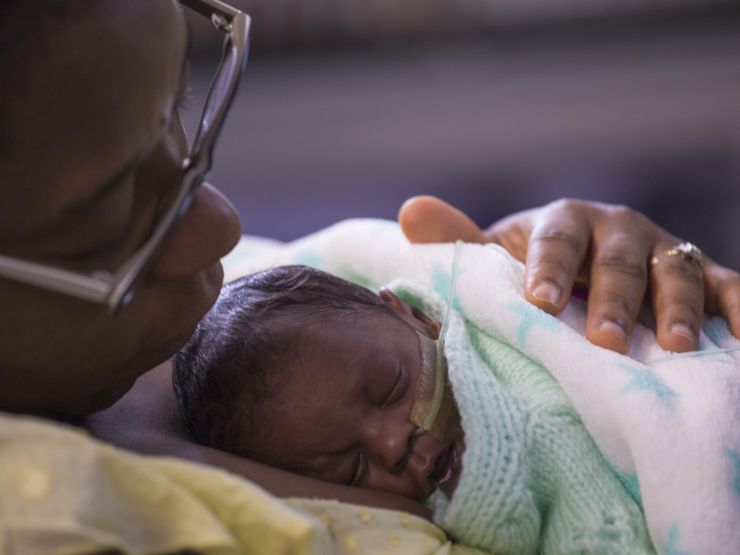 Mum holding baby on her chest looking at the baby wrapped in blankets. Baby is asleep.