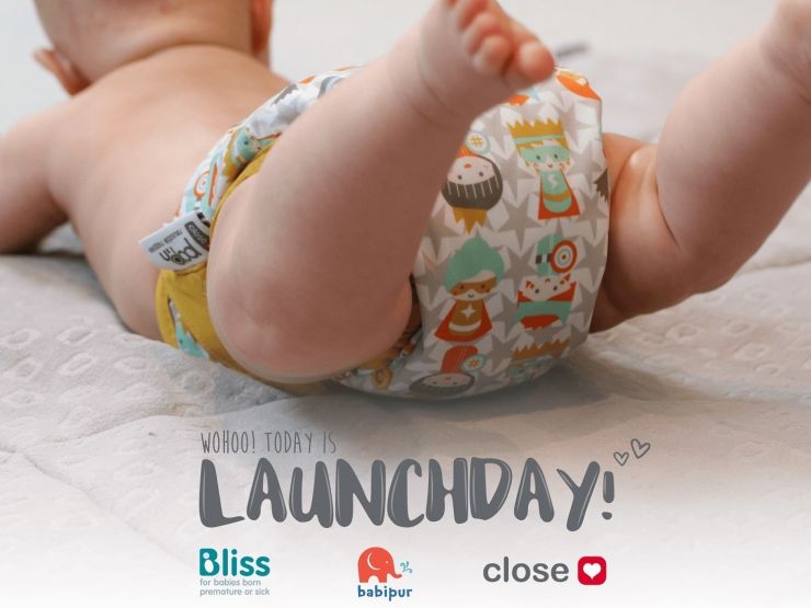 Baby wearing resuable nappy by Close Parent company, with launchday and Bliss and company logos on the image