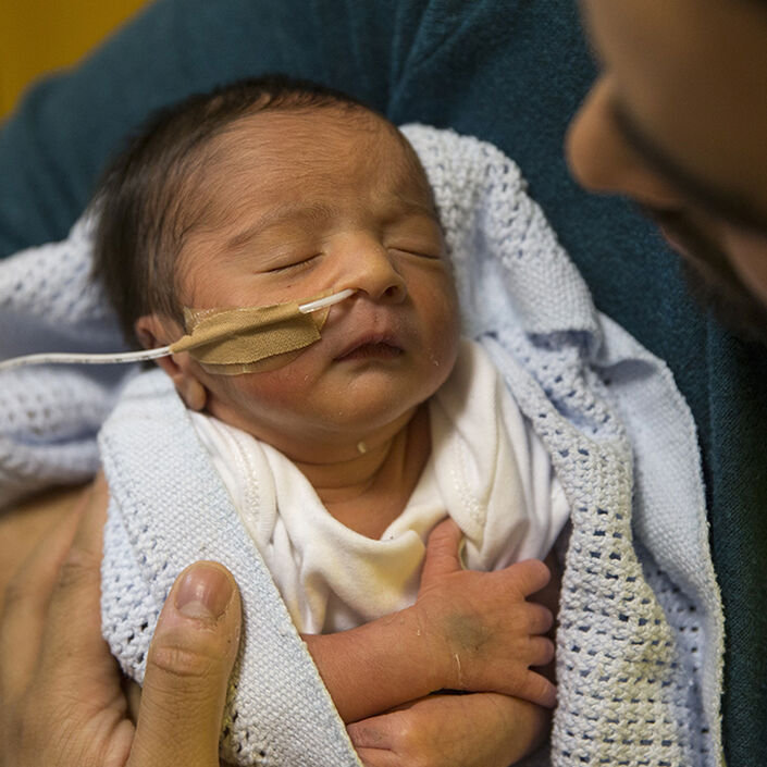 Dad holding baby looking down at baby who is asleep