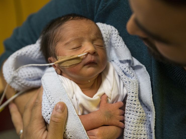 Dad holding baby looking down at baby who is asleep