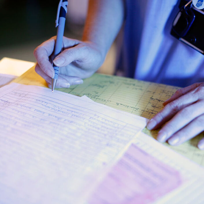 Close up of nurse holding a pen over several paper documents laid out on a desk