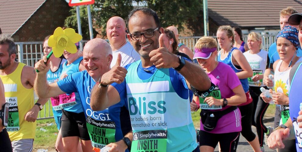 Man wearing Bliss running vest and glasses giving thumbs up as he runs