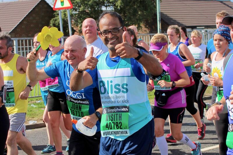 Man wearing Bliss running vest and glasses giving thumbs up as he runs