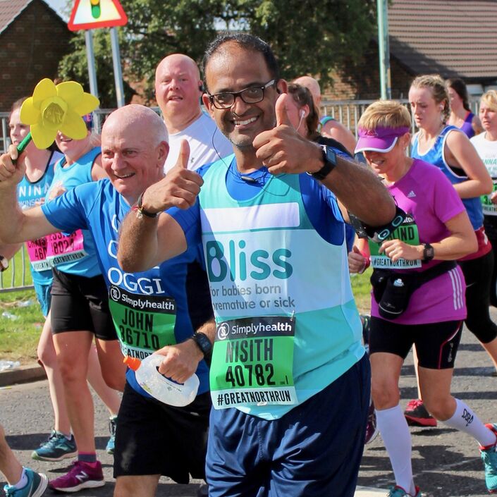 Man wearing Bliss running vest and glasses giving thumbs up as he runs