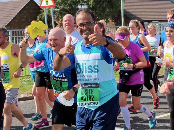 Man wearing Bliss running vest and glasses giving thumbs up as he runs