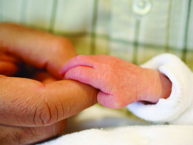 Premature baby's hand gripping parent's index finger