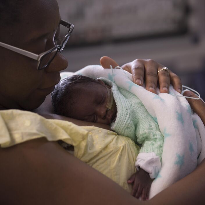 Mum holding baby wrapped in blanket on her chest