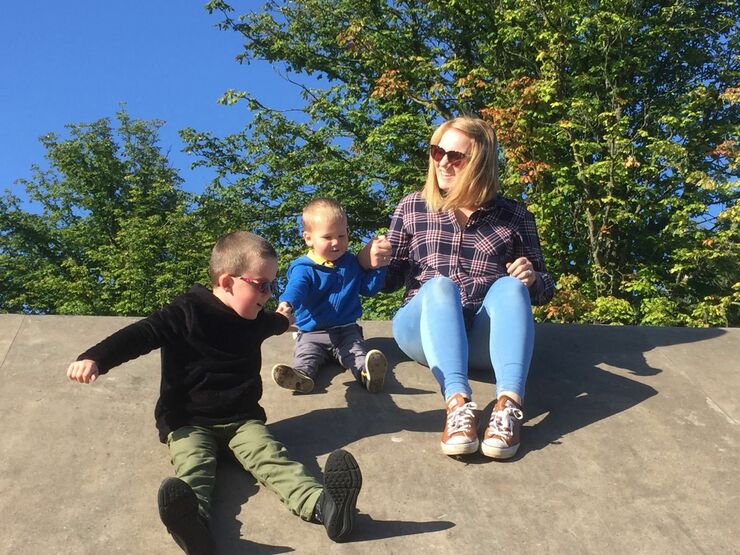 Bliss Champion Linda playing with two boys outside with trees in the background