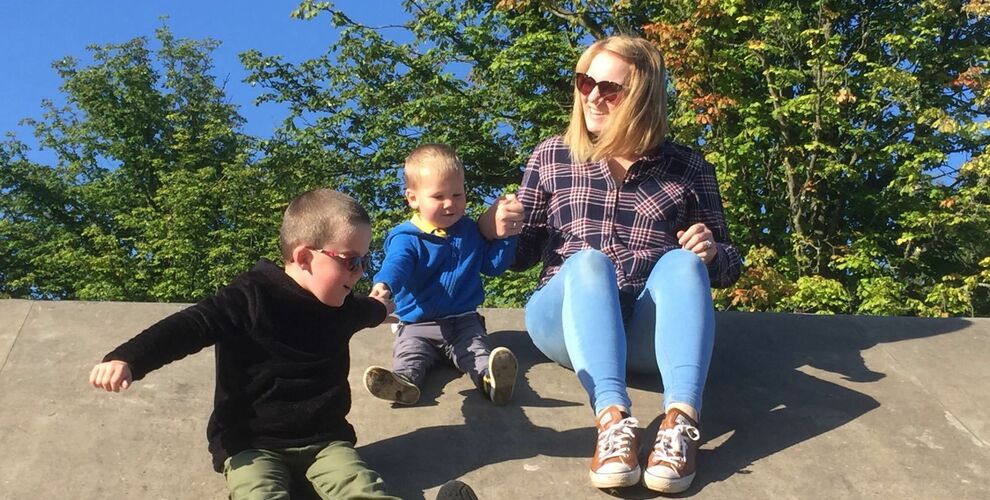 Bliss Champion Linda playing with two boys outside with trees in the background