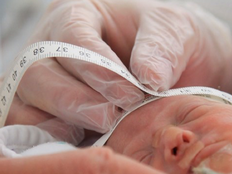 Nurse measuring a newborn baby's head circumference