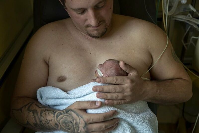 Dad holding his baby against his chest skin to skin while looking down at baby