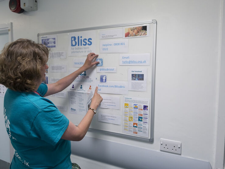 Woman with Bliss t-shirt looking at a notice board in a hospital setting