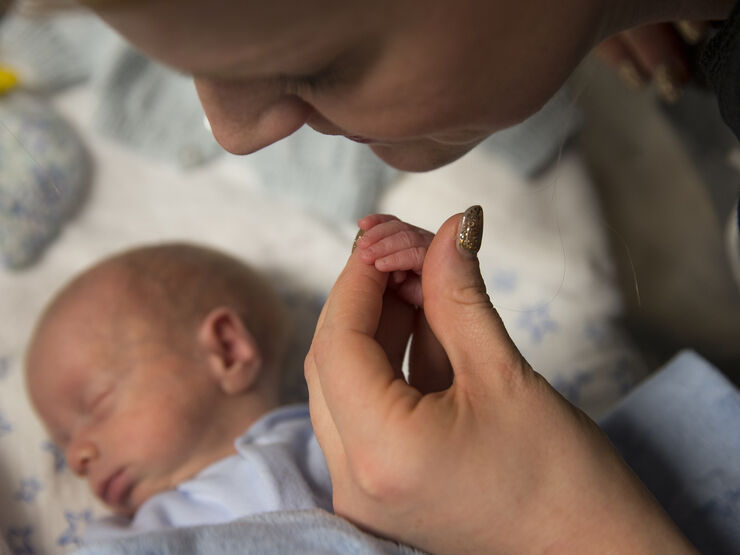 Baby asleep while mum holds his hand in hers