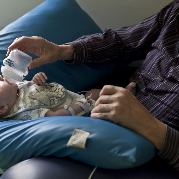 Baby resting on pillow with dad bottle feeding