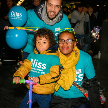 Mum, Dad and child wearing Bliss t-shirts with balloons in evening