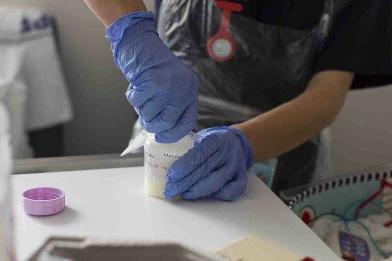 Healthcare professional with latex gloves on opening a bottle of medicine