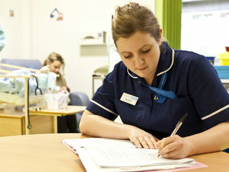 Nurse sat at a table making notes on a paper document