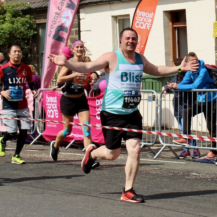 Male running the Edinburgh marathon with arms outstretched wearing a Bliss running vest